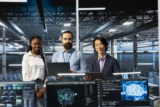 Portrait of smiling multiethnic engineers in data center troubleshooting server connectivity issues using AI. Upbeat multiracial technicians in diverse server room auditing systems for vulnerabilities photo