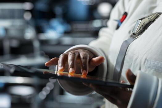 Close up of astronaut in spacecraft running diagnostics to confirm suit integrity using device. Orbital station crew member testing gear during routine equipment check, monitoring analytics photo