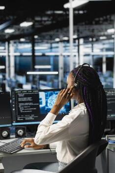 Data center operator providing user technical support, conducting remote diagnostics. Server farm IT expert managing live support calls, identifying hardware issues using predictive AI alerts photo