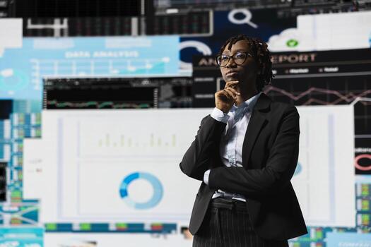 Business manager brainstorming ways to increase company profits while looking at graphs on digital screens. African american woman using insights and KPI projections for strategic decision making photo