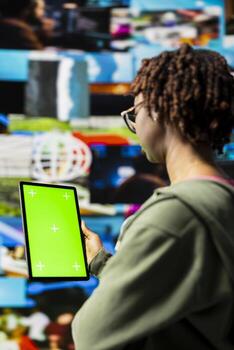 Woman engaging with multimedia dashboards using green screen tablet, showcasing power of technology and digital content. Person having fun interacting with chroma key device apps and internet websites photo