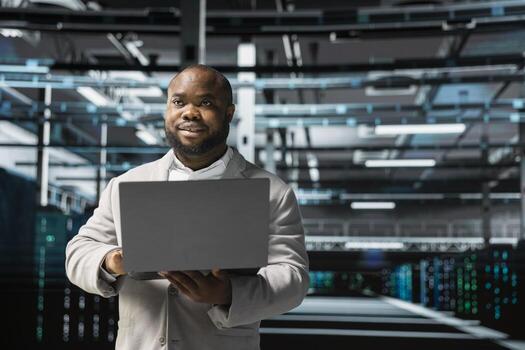 Admin in server hub checking recovery plan on laptop, monitoring data center energy consumption. Data center worker making sure sensors are functioning optimally, doing routine disk checks photo