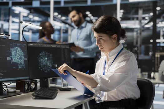Server room worker looking at AI visualization charts, reviewing documentation on clipboard ahead of audit. AI data center expert verifying configuration data and compliance standards at desk photo