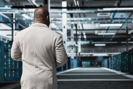 Technician walking in server room, overseeing mainframes gear used for managing databases. IT expert in data center workplace doing checkup on rackmounts storing information photo