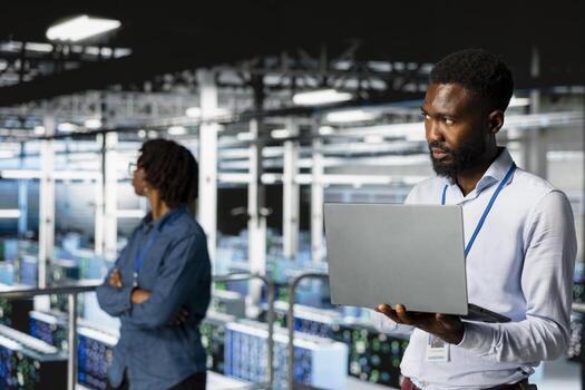 Smiling black technician and colleague in data center reviewing large language model visualizations on PC. Professional IT engineering team analyzing neural network performance outputs. photo