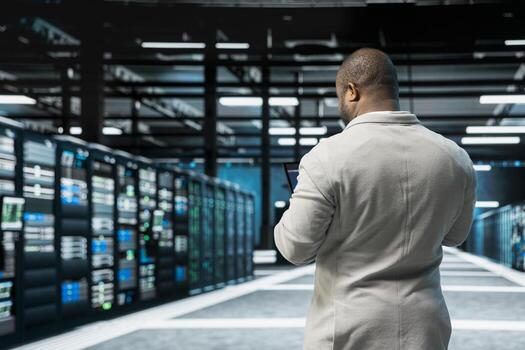 Admin in data center updating systems using tablet, conducting security audits to protect against cyber threats. Server hub IT specialist using device, deploying cybersecurity measures photo