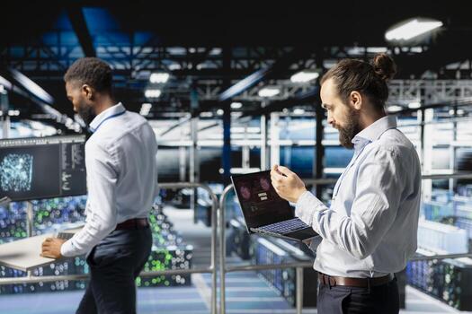 Annoyed engineer reacting to critical error message on laptop, worrying in data center. Irked IT professional attempts to resolve system fault impacting backend infrastructure performance. photo