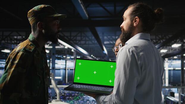 Army engineering team in command center server hub using mockup laptop to install and maintain IT systems. Military data center admins overseeing information systems with chroma key notebook, photo