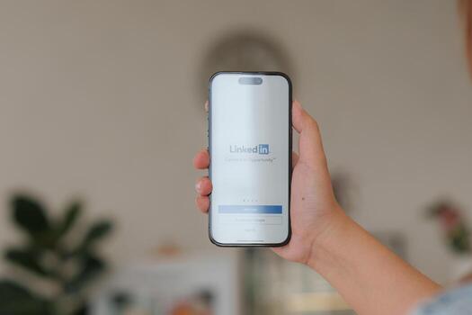 CHIANG MAI, THAILAND - FEB 12, 2023. Woman using iPhone 14 with LinkedIn application on the screen. LinkedIn is a business-oriented social networking service photo