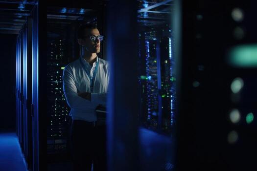 Administrator monitors server performance in dimly lit server room photo