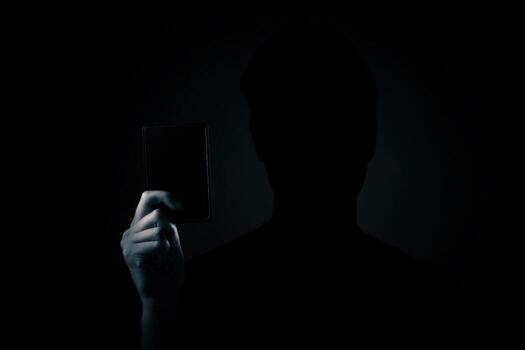 Mysterious figure holds a dark object while silhouetted against a shadowy background photo
