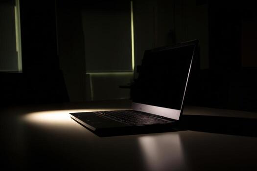 Dark office with glowing laptop left open in quiet atmosphere photo
