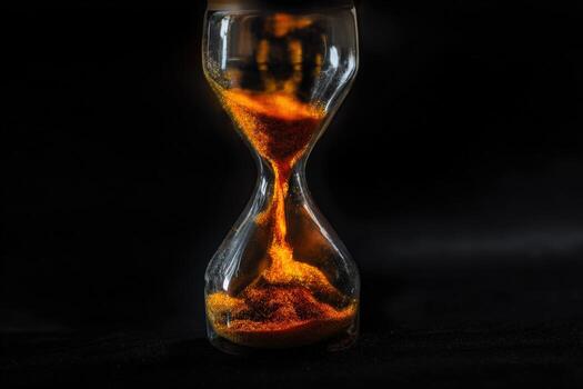 Conceptual representation of an hourglass with flowing colored powder and a dark backdrop photo