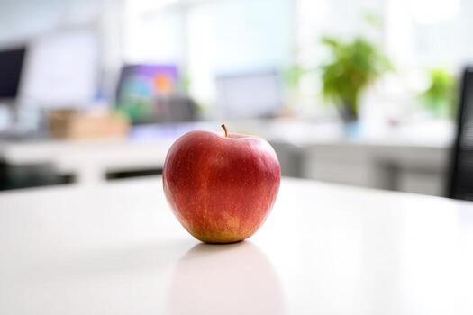 Fresh red apple placed on a white desk in a bright office setting photo