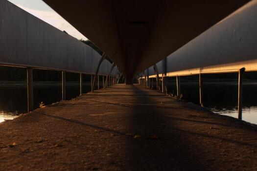 Fading light over a serene bridge leading to the horizon at sunset photo