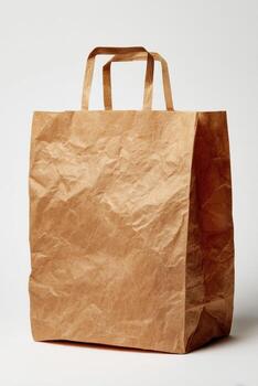 A textured brown paper bag with handles stands against a plain white background photo
