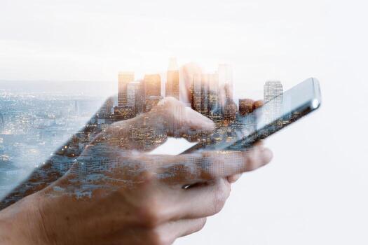 Hands using smartphone, superimposed with city skyline, bathed in morning or evening light photo