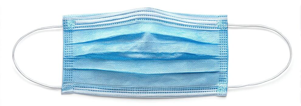 A light blue surgical mask with pleats and ear loops, resting on a white surface photo