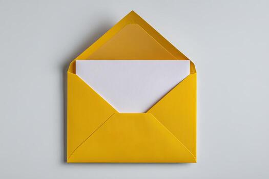 Open yellow envelope revealing a blank white paper, flat lay on a gray surface photo