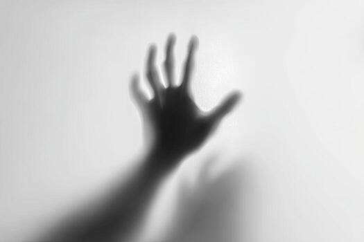 A grayscale image shows a hand reaching out, blurred and indistinct against a white backdrop photo