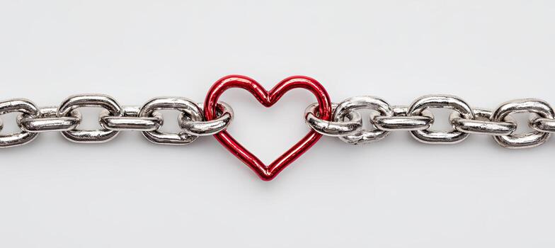 A shiny silver chain is connected to a red heart-shaped link on a bright white background photo