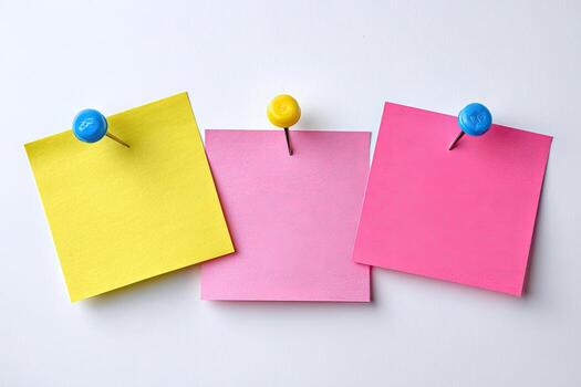 Three colorful sticky notes, yellow, pink, and magenta, pinned to a white surface photo