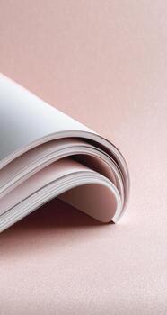 Curled open book showing stacked pages, soft focus against a light pink, smooth background photo