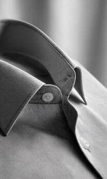 Close-up grayscale of a button-down collar and upper shirt. Focus on detail photo