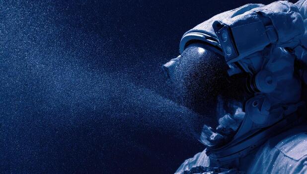 An astronaut, viewed in profile, is engulfed by a cloud of fine particles. Deep blue color photo
