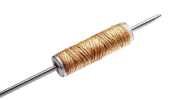 de cerca de un dorado hilo carrete con un metal aguja foto