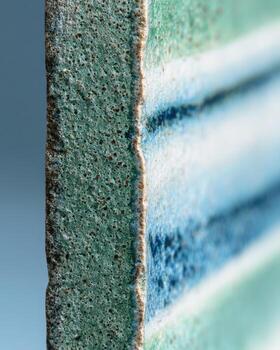 Close-up of a ceramic tile, showing a textured edge and horizontal bands of color photo