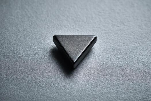 Close-up of a dark gray, matte triangle on a textured gray surface photo