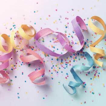 Pastel-colored party streamers and confetti scattered on a light-colored background photo