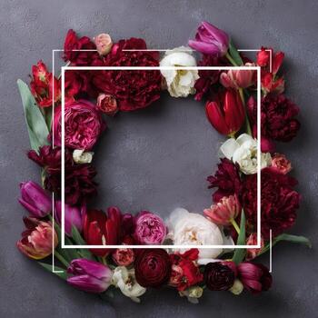 Overhead view of a square white frame surrounded by vibrant red, pink, and white flowers photo