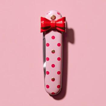 Pink swiss army knife adorned with red polka dots and a matching bow on a pink backdrop photo