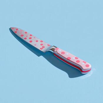 A colorful, patterned kitchen knife casts a shadow on a light blue surface, angled photo