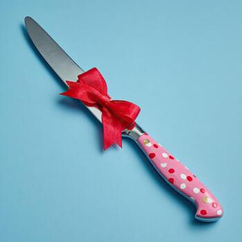 A decorative knife wrapped with a red bow on a light blue background photo