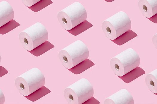 Patterned arrangement of white paper rolls with shadows, set against a vibrant pink backdrop photo