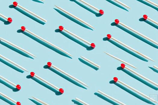 Pattern of matchsticks with red tips and long shadows on a blue background photo