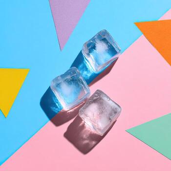 Three translucent ice cubes cast shadows on a vibrant geometric abstract background photo