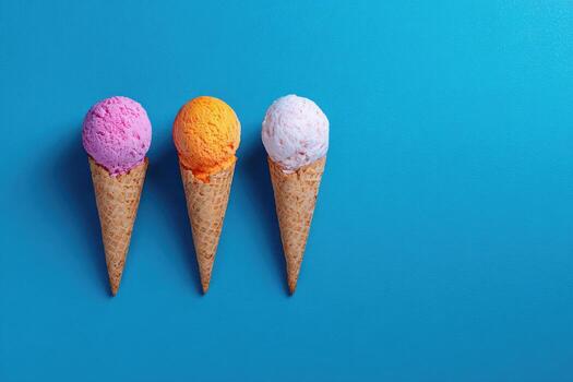 Three colorful ice cream cones with matching scoops against a vibrant blue backdrop photo