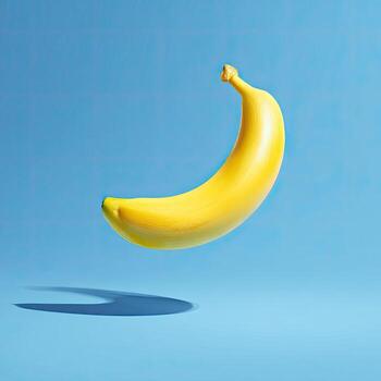 Bright yellow banana floats against a gradient blue backdrop, casting a distinct shadow below photo