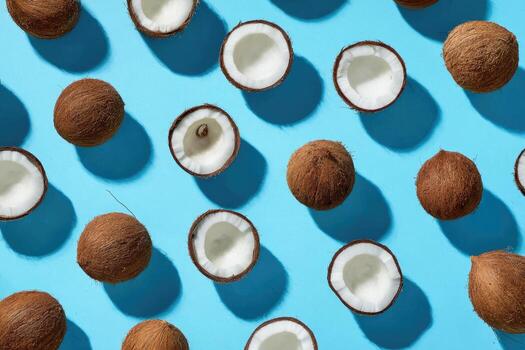 Overhead shot of whole and halved brown coconuts scattered on a vibrant blue surface photo