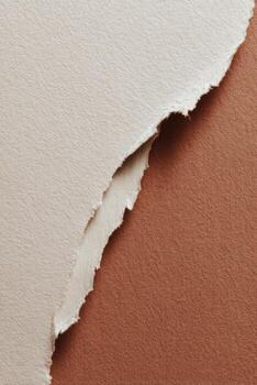 Close-up of torn, textured off-white paper revealing a contrasting tan background photo