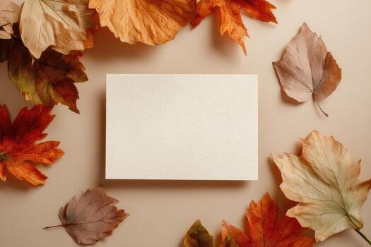 A blank card surrounded by autumn leaves on a neutral surface, inviting text photo