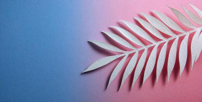 Delicate paper palm leaf against a gradient blue-pink backdrop, creating soft shadows photo