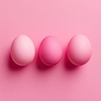 Three pastel pink eggs of varying shades arranged neatly against a smooth, matching backdrop photo