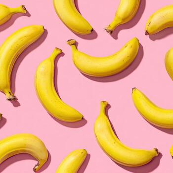 A vibrant pink backdrop is covered with a repeating pattern of bright yellow bananas photo