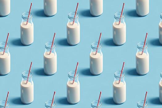 A pattern of small, glass bottles filled with white liquid and red-striped straws on a light blue surface photo