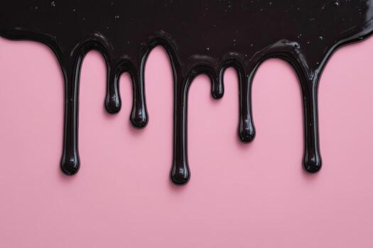 Close-up of viscous, dark liquid dripping down a smooth pink background photo